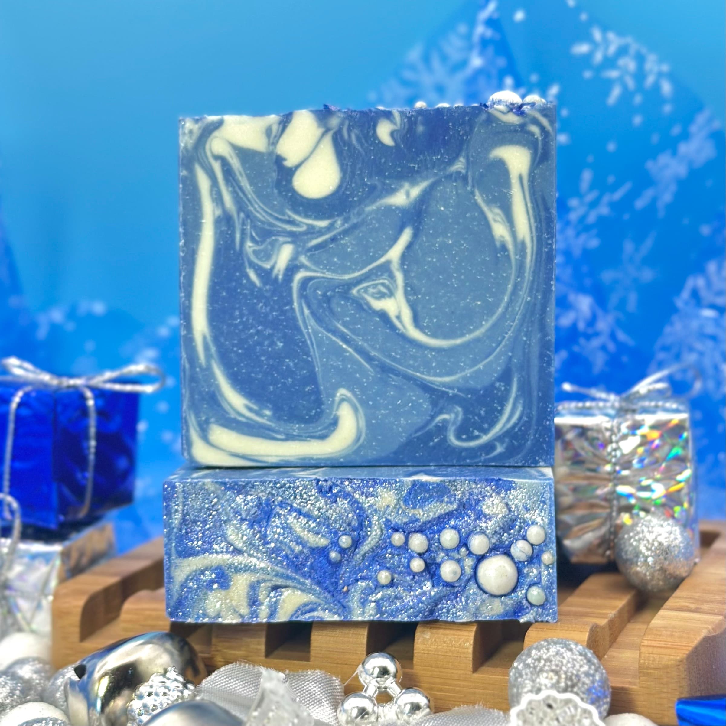 Blue and white marbled soap bar with swirled pattern on top, displayed on wooden soap dish. Bottom portion features textured blue surface with raised white bubble design.